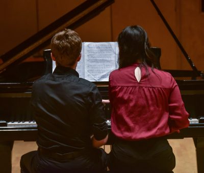 Young artists reading sheet music off of piano bench