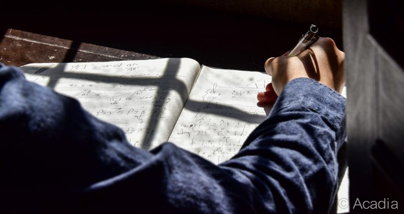 Composer writing music on sheet of paper